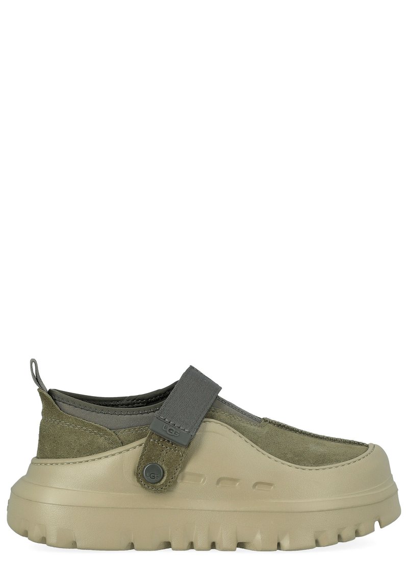 Scarpa slip-on in camoscio verde con suola in gomma beige, cinturino regolabile e tomaia testurizzata per una migliore aderenza e comfort.