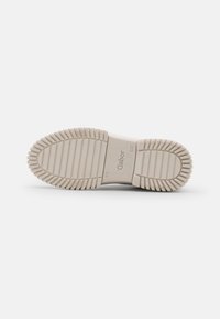 Light beige rubber shoe sole with textured ridges and logo. Flat design, wide tread for grip. Clean lines without additional embellishments.