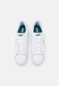Sneaker bianche in pelle con lacci piatti, dettagli verdi sulla linguetta e sul tallone, e un logo dorato lateral.