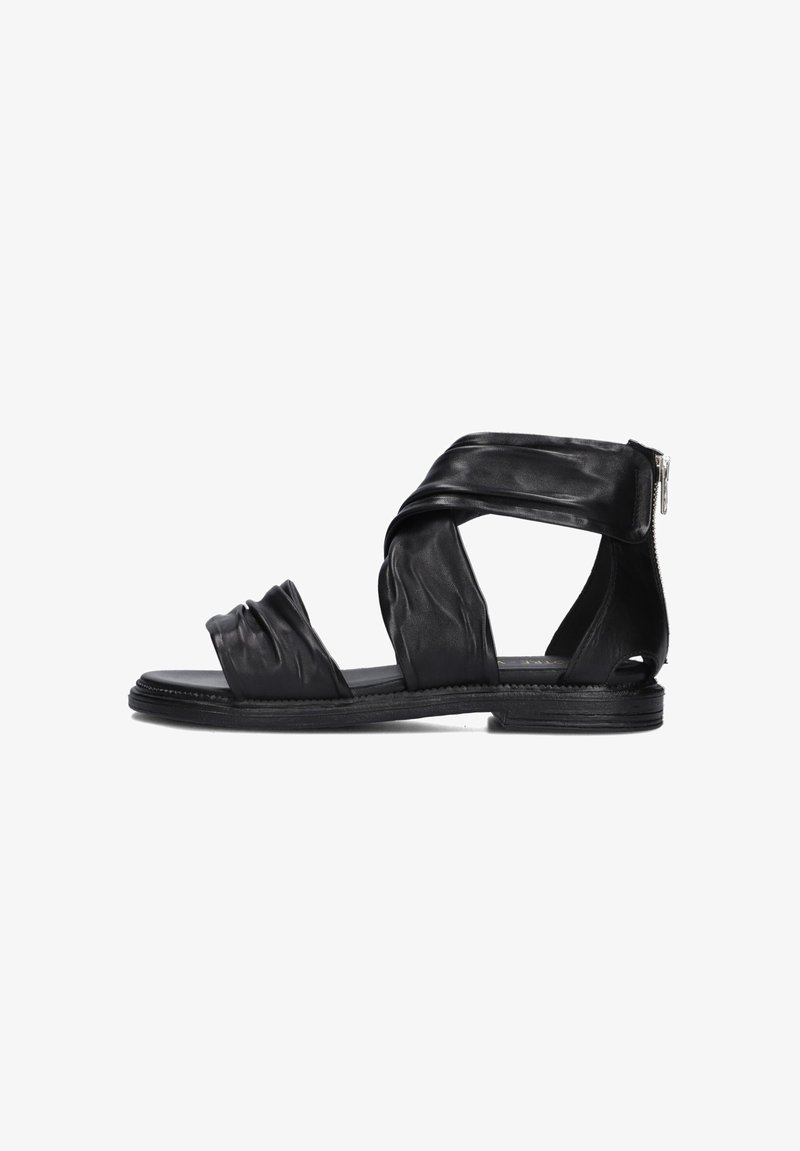 Black leather sandals featuring crisscrossed straps, a ruched front detail, and a rear zipper. Flat sole with a textured finish.