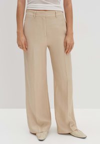 Pantalons large beige en tissu léger avec une texture lisse, dotés d'un pli avant et d'une ceinture tailleur.