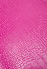 Kirkas vaaleanpunainen pinta, jossa on kiiltävä, kohokuvioitu krokotiilinnahkatekstuuri, jossa on epäsäännöllisiä suorakulmaisia ja soikeita suomuvioita.
