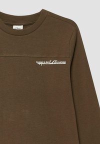 Bruine langemouwen shirt met geribbeld col en witte tekst "EEN DAG IN DE NATUUR" nabij de borst, met een kleine plant graphic.