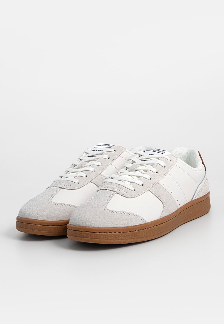 Weiße Sneaker mit hellgrauen Wildlederakzenten, strukturiertem Gummisohle, flachen Schnürsenkeln und einem Branding-Tab auf der Zunge. Sie verfügen über ein Obermaterial aus glattem Leder.