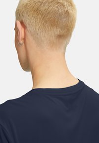 Marine sports T-shirt med en glat tekstur, rund halsudskæring og diskret præglogo på ryggen. Kort hår synligt i billedet.