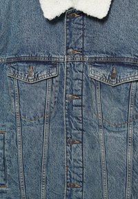 Veste en denim avec col en peau lainée, cinq boutons métalliques sur le devant et deux poches poitrine à rabat boutonné.