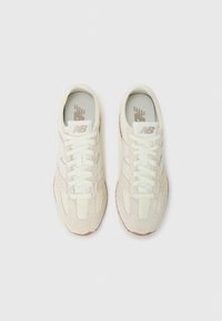 Paire de baskets New Balance blanches avec empiècements en daim et en mesh, vues de dessus sur un fond clair et uni.