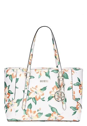 Sac fourre-tout blanc Guess avec motif floral orange et vert, deux bretelles et un pendentif rond argenté avec le logo suspendu à une des bretelles.