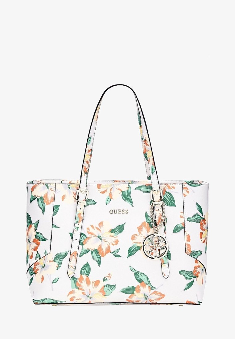 Sac fourre-tout blanc Guess avec motif floral orange et vert, deux bretelles et un pendentif rond argenté avec le logo suspendu à une des bretelles.