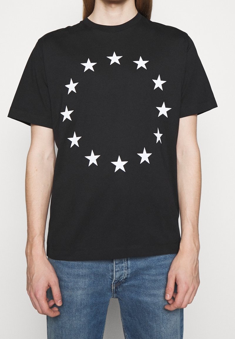 Černé bavlněné tričko s kulatým uspořádáním bílých hvězd potištěných na přední straně, s klasickým kulatým výstřihem a krátkými rukávy.