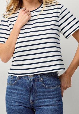 Wit T-shirt met ronde hals en marineblauwe horizontale strepen, korte mouwen en een losse pasvorm, gecombineerd met een high-waisted blauwe jeans.