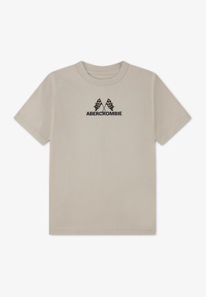 Beige t-shirt med korte ærmer med to krydsede sorte ternede flag og teksten "ABERCROMBIE" nedenunder, centreret på brystet.