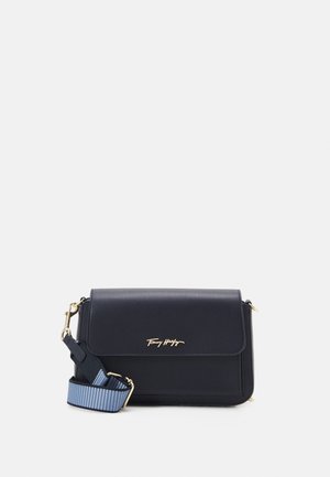 Zwarte rechthoekige crossbodytas met gouden logoletters en verstelbare blauw gestreepte stoffen band op een witte achtergrond.