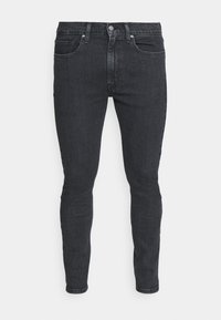 Jeans de mezclilla oscura ajustados con una textura suave, diseño de cinco bolsillos y cierre de botón clásico. La tela parece robusta y uniforme.