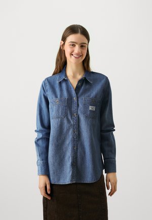 Blue denim shirt with long sleeves, button-up front, two chest pockets, and a slightly textured finish. Casual design with collar detail.
