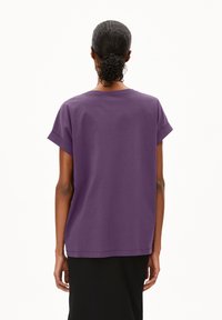 Paarse kraagloze t-shirt met korte mouwen, gemaakt van zacht katoen. Heeft een ronde hals en een relaxte pasvorm met opgerolde mouwen, gezien vanuit de achterkant.