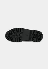 Czarna gumowa podeszwa buta z głębokimi bieżnikami, okrągłymi wzorami blisko przodu oraz małym logo Jumpman na środku.