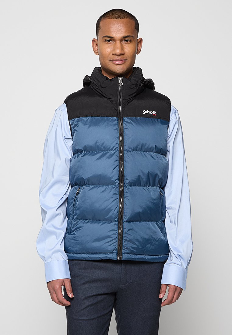 Gilet rembourré bleu avec un col noir, doté d'une fermeture zippée, de deux poches latérales et du logo Schott sur la poitrine gauche. Le matériau est brillant et lisse.
