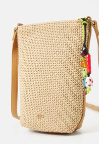 Bolso de paja tejido tipo bandolera con una correa de cuero marrón claro. Presenta acentos de cuentas coloridas adheridos al cierre. Forma rectangular compacta.