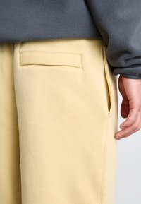 Nike Sportswear CLUB PANT - Tepláky - team gold