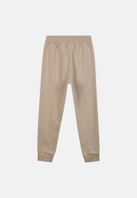 Beige joggingbroek gemaakt van zachte stof met een elastische tailleband en boorden bij de enkels; gladde textuur zonder zichtbare patronen of accenten.