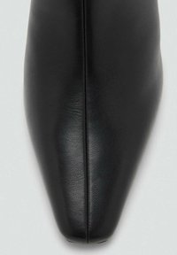 Zapato de cuero negro con punta afilada, textura suave y costura central que recorre la parte superior. Diseño minimalista y sin herrajes visibles.