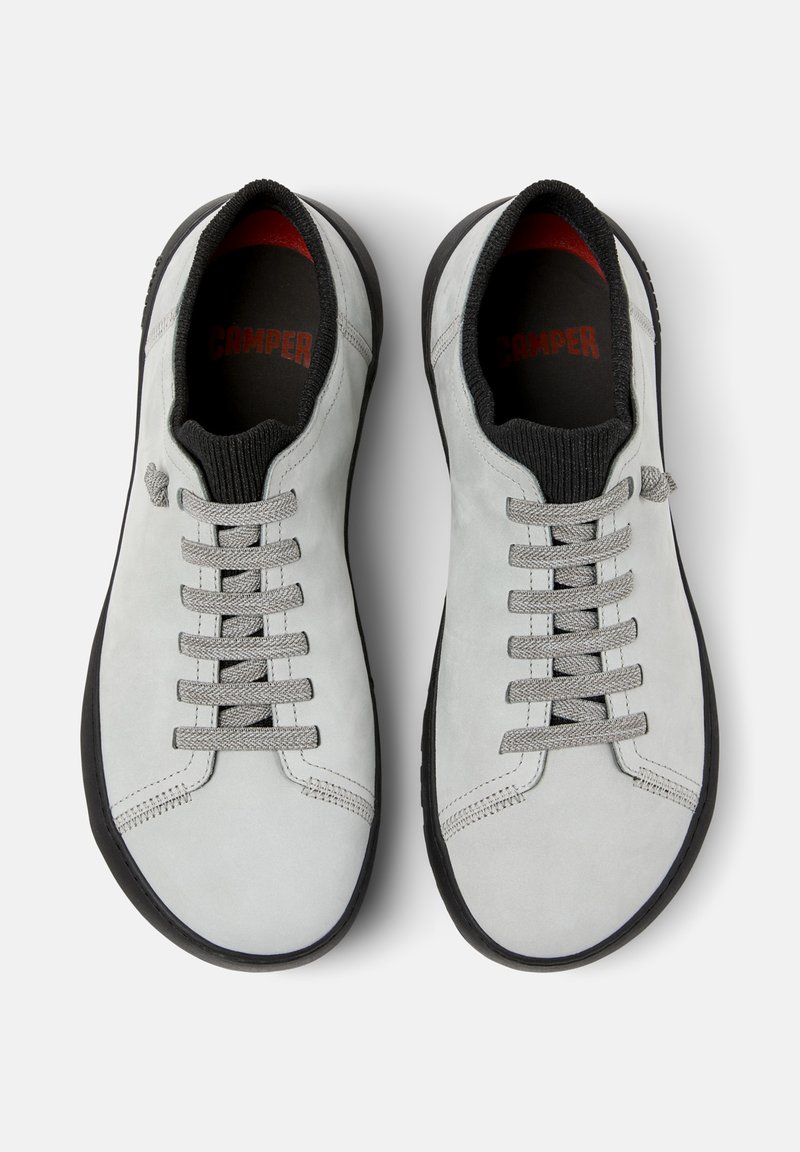 Gray suede sneakers featuring a low profile, round toe, black rubber sole, and gray laces. Interior has a black lining with red accents.