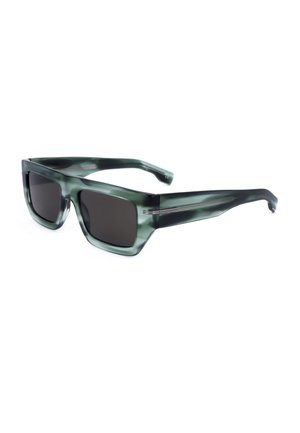 Occhiali da sole rettangolari con fantasia mimetica verde, lenti scure e aste spesse, mostrati con una leggera inclinazione su sfondo bianco.