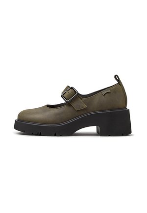 Zapato Mary Jane verde oliva con tacón grueso negro, correa ajustable con hebilla, lazo lateral y suela texturizada.