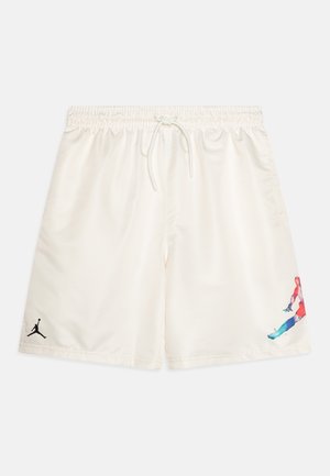 Shorts de sport blanc cassé avec taille élastique et cordon, avec un petit logo noir sur une jambe et une silhouette colorée sautillante sur l'autre.
