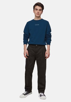 Blauwe sweatshirt met logo, zwarte broek en zwarte sneakers. Casual ontwerp met ribgebreide manchetten en een relaxte pasvorm.