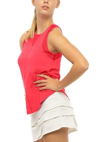 Débardeur de sport rose ajusté avec des coutures contrastées, un col rond et des détails en mesh, associé à une jupe blanche superposée.