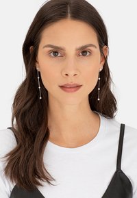 Silberne Tropfhängerohrringe mit einem linearen Design und runden Perlenakzenten, die eine schlanke und glänzende Oberfläche präsentieren.