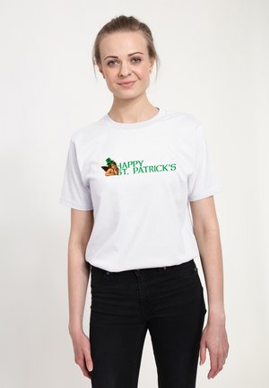 T-shirt en coton blanc avec un texte vert "Happy St. Patrick's" et un graphique d'un leprechaun portant un chapeau vert. Design simple, manches courtes.