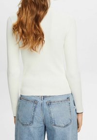 Vit ribbad långärmad topp med en tight design, parat med ljusblå högmidjade jeans i denim med bakfickor.