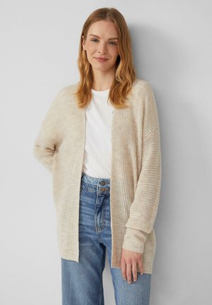 Beżowy sweter dzianinowy z otwartym przodem i długimi rękawami, noszony na białym t-shircie, zestawiony z niebieskimi dżinsami z wysokim stanem. Teksturowany materiał.
