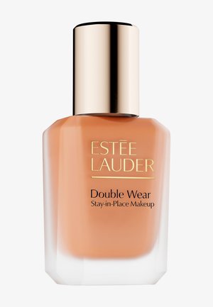 Fondotinta Estée Lauder Double Wear in una bottiglia di vetro trasparente dalla forma geometrica; presenta un tappo dorato e un liquido visibile in una tonalità beige calda.