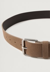 Cinturón de ante marrón con una banda oscura y suave y una hebilla de metal plateado. Presenta múltiples agujeros para el ajuste y un diseño minimalista.
