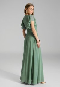 Muntgroene chiffon jurk met vloeiende mouwen en gerimpelde taille. Lange, luchtige rok met een gladde textuur, elegante rugontwerp.