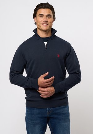 Navy blue quarter-zip pullover made of cotton blend, featuring ribbed cuffs and hem, with a small red logo on the chest. Casual fit.