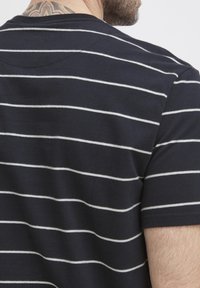 Tamsiai mėlyna marškinė su baltomis horizontaliomis juostelėmis, apvaliu kaklu ir trumpomis rankovėmis. Pagamintos iš medvilnės, su glotnia tekstūra.