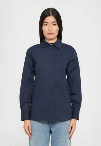 Chemise bleu marine à boutons en tissu léger avec un col classique, des manches longues et un ourlet droit. Aucun motif ou accent visible.