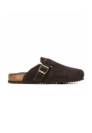 Zueco marrón oscuro tipo slip-on con empeine de ante, correa ajustable con hebilla, suela de corcho y forro interior peludo.