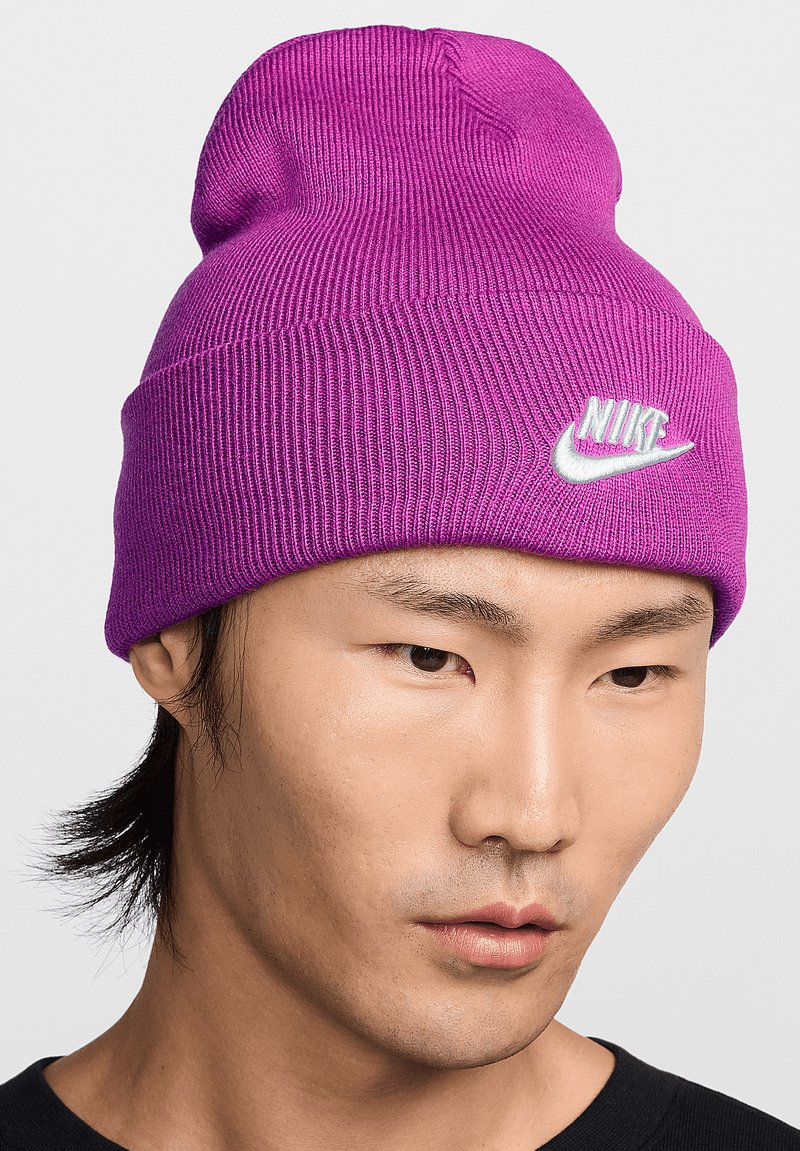 Beanie viola a maglia con una texture rigata e un bordo arrotolato, caratterizzato da un logo Nike bianco cucito sulla parte anteriore.