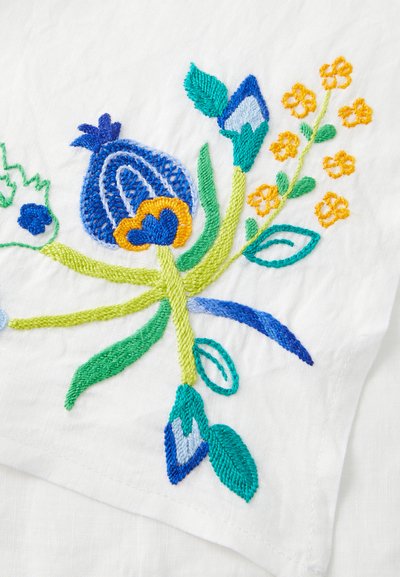Tessuto bianco con ricami floreali colorati in blu, giallo e verde, con fiori e foglie dettagliati ricamati con varie texture.