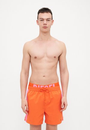 Shorts de bain pour homme de couleur orange vif, avec une ceinture et des accents de marque en rose, et une conception en tissu lisse et léger.