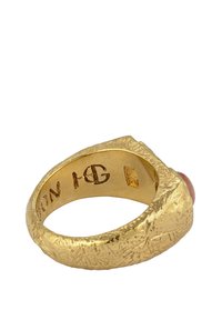 Guldring med en strukturerad yta, prydd med en stor rödbrun sten som är inställd på toppen. Graverade detaljer inuti ringen.