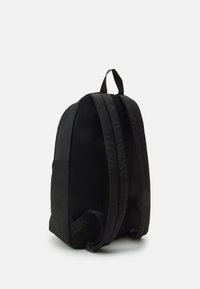 Zaino nero con spallacci laterali in rete imbottita, maniglia superiore e un esterno in tessuto liscio e testurizzato. Design minimalista senza motivi visibili.