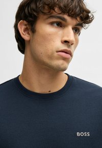 Navy gebreide sweatshirt met een ronde halslijn en een subtiele "BOSS" logo in witte borduursel op de borst. Zachte textuur en aansluitend ontwerp.