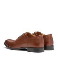 Zapatos de vestir de cuero marrón con un acabado suave, diseño con cordones, punta ligeramente redondeada y suela de goma negra.